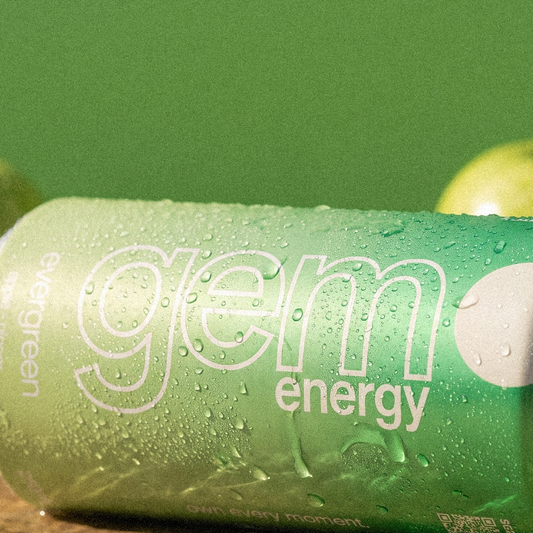 Close-up of a chilled Gem Energy Evergreen can lying on its side next to green apples