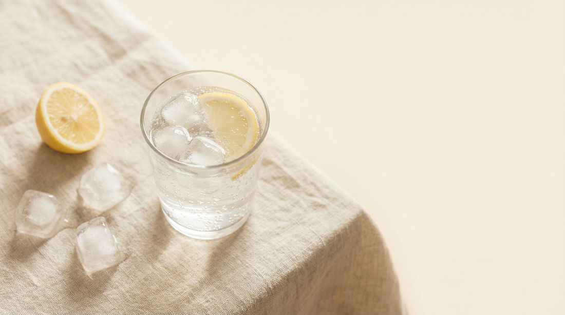 Ginger Sparkle in a glass with ice and a lemon slice on a linen tablecloth